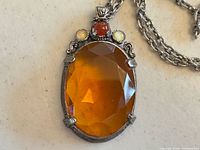 Front view showing amber glass cabochon and accent stones