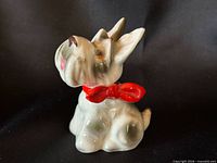 Front angled view of seated porcelain Scottie with red bow