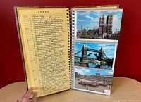 Album open showing handwritten index page and three European landmark postcards in plastic sleeves