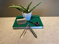 Pipe, straight razor, pumice stone displayed on book