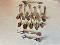 Group shot of 12 spoons and 2 forks arranged on tabletop