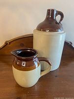 Front view of large jug and small cream pitcher showing beige bodies and brown drip glaze