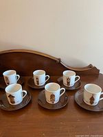 Six cups and six saucers arranged on wooden surface