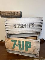 Three crates stacked showing 7UP, Nesbitt’s, Burns