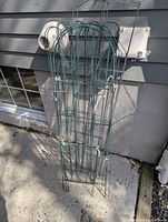 Stack of green wire arched panels leaning against wall