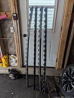 Four black plastic edging strips leaning against a door