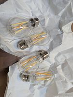 Four clear filament Philips Hue bulbs on paper