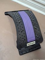 Front view showing COSCANA brand label, purple padded strip, acupressure nodes, and folding hinge