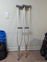 Front view of pair of aluminum crutches leaning against wall