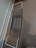 Full view of chrome metal bathtub caddy with white handles