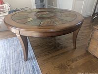 Front angled view of round wood coffee table with stone inlay