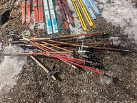 Pile of assorted ski poles on ground