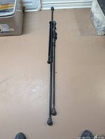 Three black metal extendable curtain rods laid flat showing finials and rod length