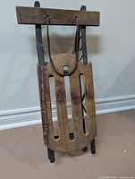 Full view of wooden child’s sled with rope pull