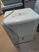 Front view of white Mainstays dehumidifier showing grille, control panel and cord