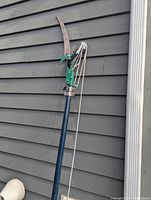 Full view of pole saw lopper leaning against wall