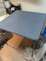 Overall view of square folding card table showing top surface and legs