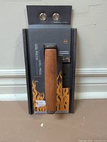 Front view of packaged cast iron grill press with wood handle