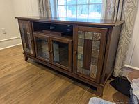 Front view of media console showing side slate tile doors, glass center doors
