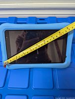 Front view of tablet in blue padded case with measuring tape showing ~8-inch screen