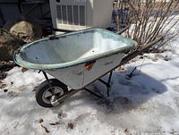 Left side view of child-size wheelbarrow on snow