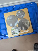 Front view of wood board with five metal discs and hardware bag