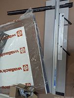 Logan Simplex Elite mat cutter with rail and base board leaning against wall, accessories visible in box