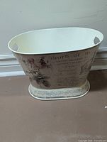 Front view of oval metal basket showing floral print and handles