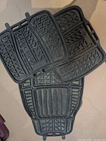 Three black Michelin rubber floor mats stacked showing tread pattern and attachment tabs