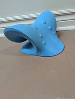 Side view of blue contoured neck stretcher showing raised nodes and curved shape