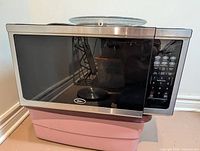 Front view of Oster stainless steel microwave oven with glass turntable set on top