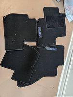 All four black carpet floor mats showing embroidered Outlander logo patches