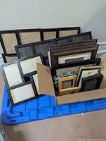 Group of assorted photo frames stacked in bin and box