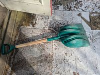 Full view of green plastic snow shovel on ground