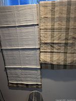 Two Roman shades hung side by side showing full length, color, pattern and cord structure