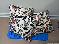 Three patterned throw pillows arranged on floor against wall