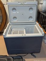 Coleman electric cooler with lid open showing interior, shelf divider and vented tray