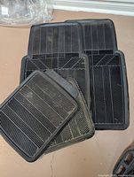 stack of four black ribbed rubber car mats