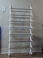 Full view of the white wall-mounted rack showing eight metal rods and side brackets