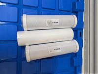 Three cylindrical RO filter cartridges on blue surface