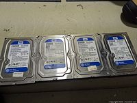 Four WD Blue 250GB hard drives laid out side by side showing labels and model information