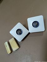 Two white square chimes and beige door sensor pieces displayed together