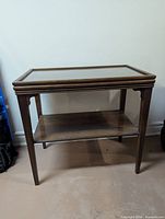 Full view of the wooden end table with glass top and lower shelf