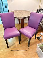 front view of two purple dining chairs with black legs