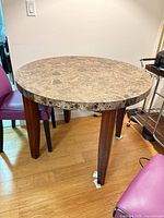 Full view of round marble dining table, wooden legs visible