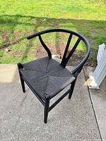 Full view of one black wood dining chair on patio