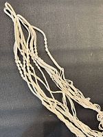 Close-up of knotted cotton cords and fringe of macrame hanger