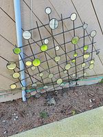 Full view of square metal grid wall art with multiple circular mirrors