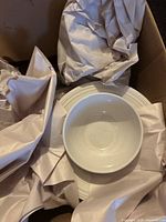 white bowl on stacked white plates in box