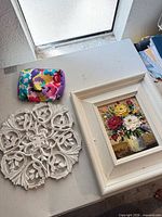 All three items together: framed painting, carved medallion, fabric pouch